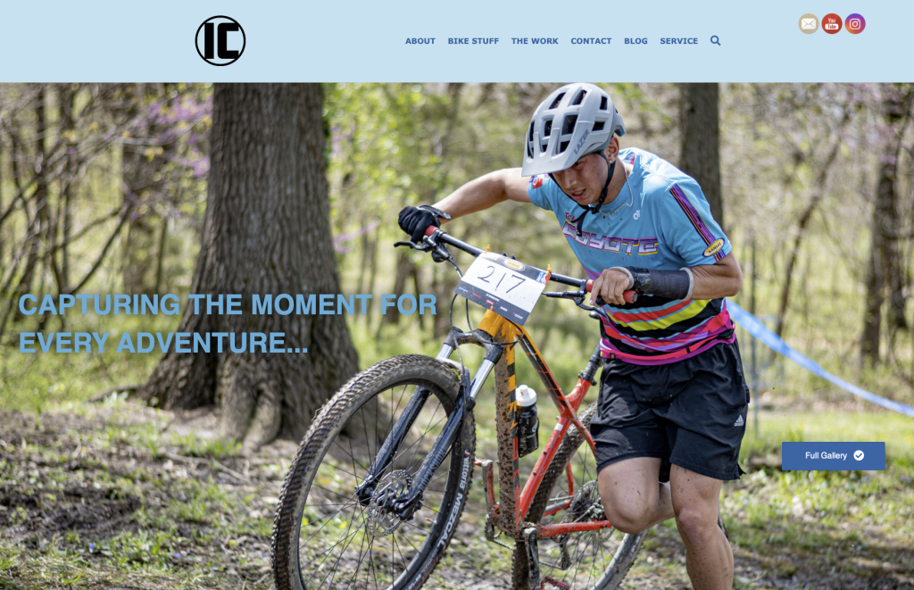 Screenshot of webpage created by student. Blue header with navigational text. Large photo of person pushing a bike with text: Capturing the moment for every adventure.